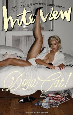 Doja Cat laying on a white bed with one leg raised on the cover of Interview Magazine